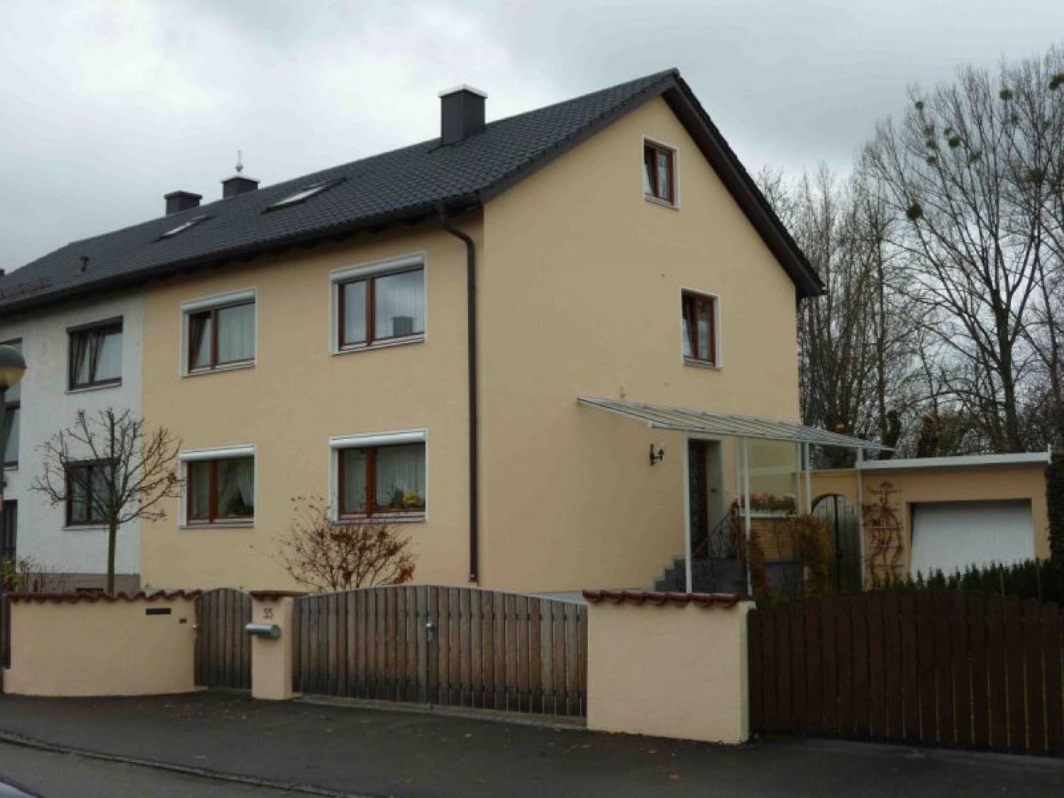 Mehrfamilienhaus mit neu gestrichener heller Fassade und Sockelanstrich