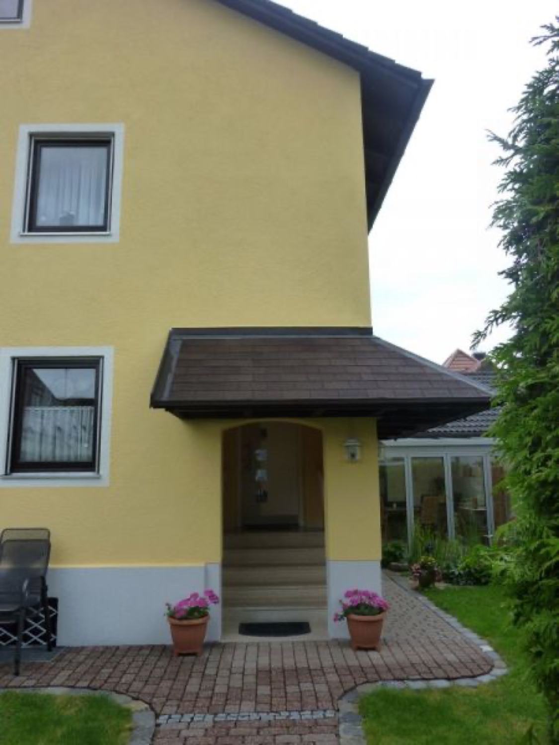 Frisch gestrichene gelbe Hausfassade mit Eingangsvordach, ausgeführt vom Malerbetrieb Zauke